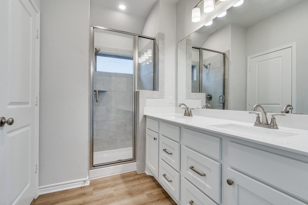 a white bathroom with two sinks and a shower