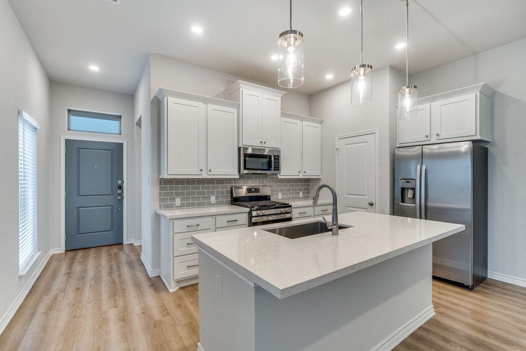 an open kitchen with white cabinets and a marble counter top