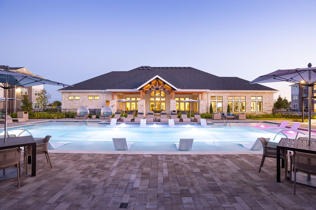 a resort style pool with lounge chairs and umbrellas