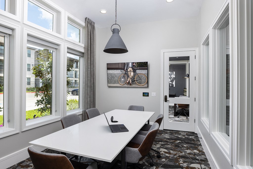 a meeting room with a white table and chairs and a laptop on top of it