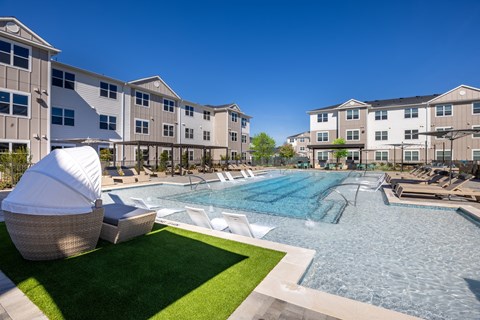 a swimming pool with lounge chairs and umbrellas in front of an apartment building