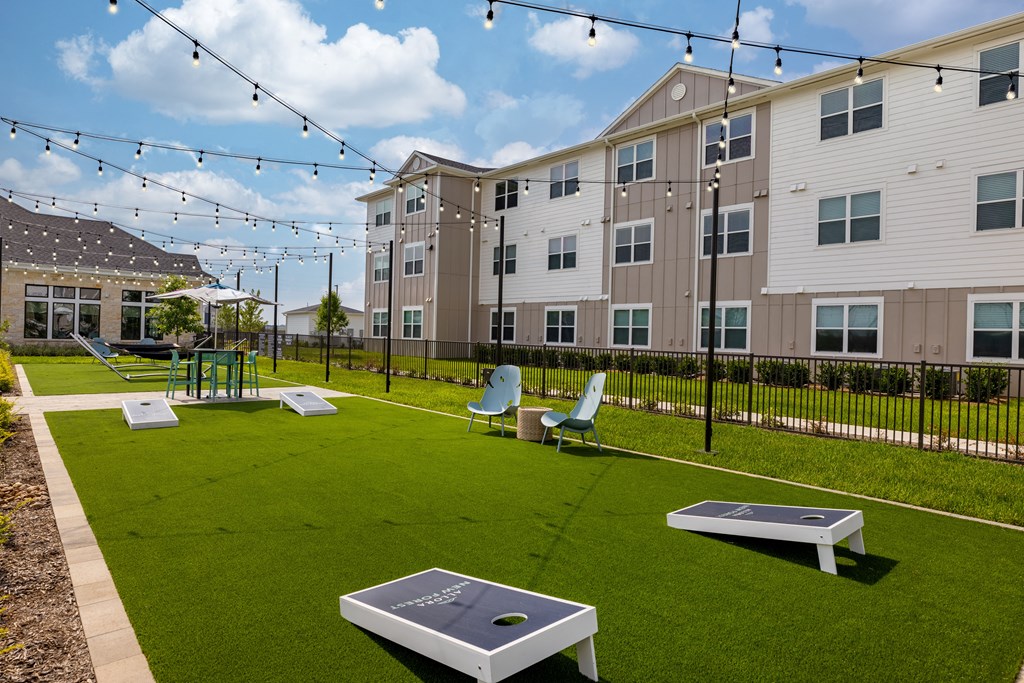a grassy area with ping pong tables and lounge chairs