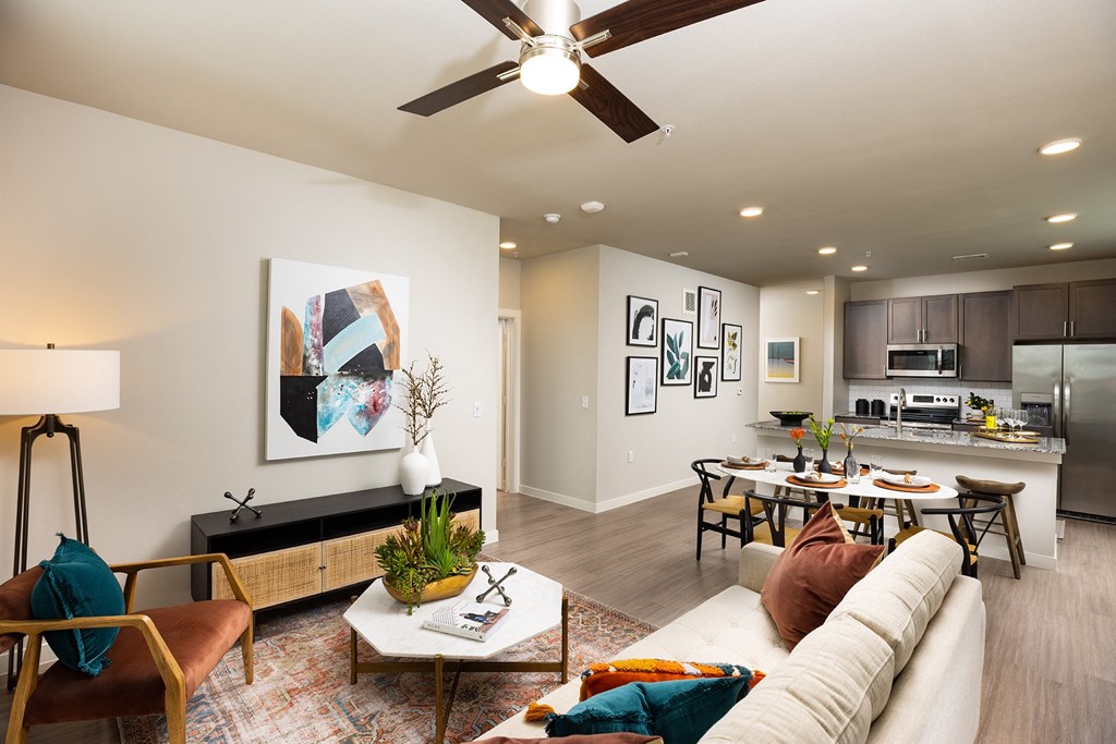 our apartments offer a living room with a couch a dining table and a kitchen with stainless steel