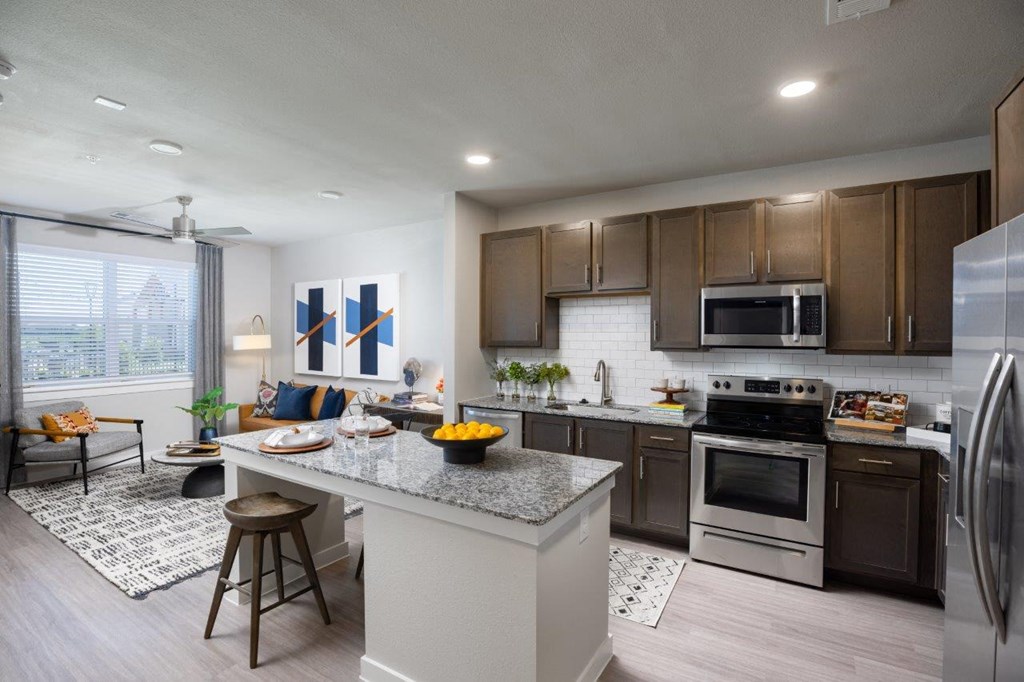 an open kitchen and living room with a large island with a granite countertop