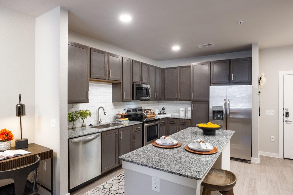 kitchen with stainless steel appliances and granite countertops at the district flats apartments in lenexa