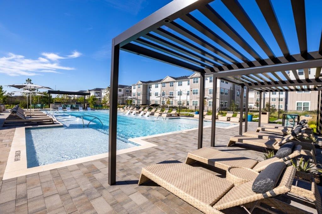 a pool with lounge chairs and umbrellas at the resort on a sunny day
