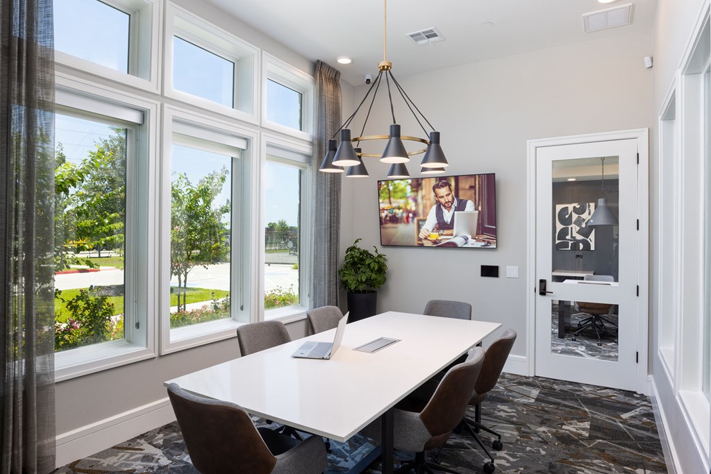 a meeting room with a white table and chairs and a tv on the wall