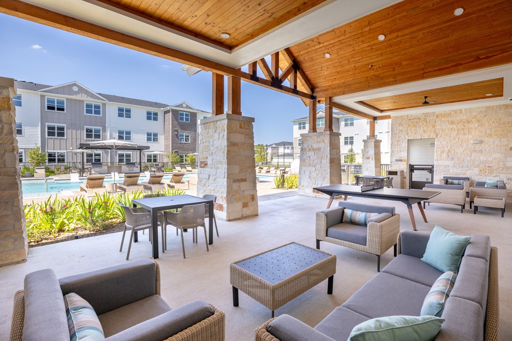 a patio with couches tables and chairs and a pool in the background
