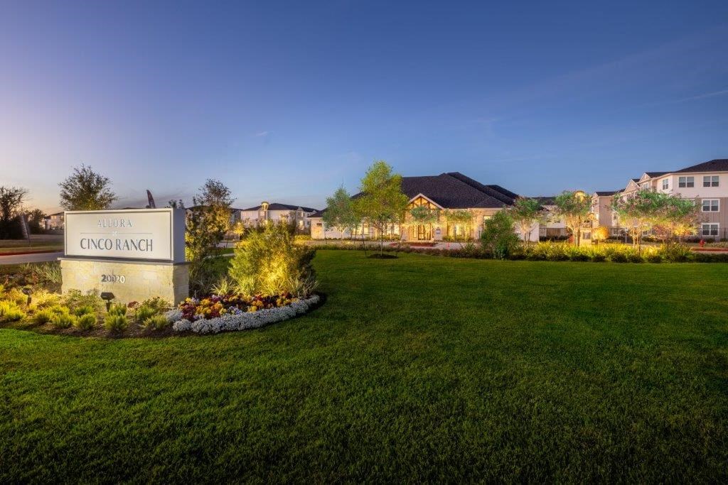 a rendering of the concierge sign at dusk in front of a green lawn