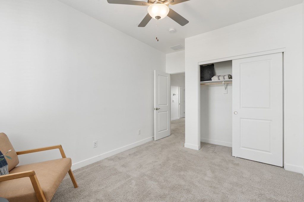 A room with a ceiling fan and a chair.