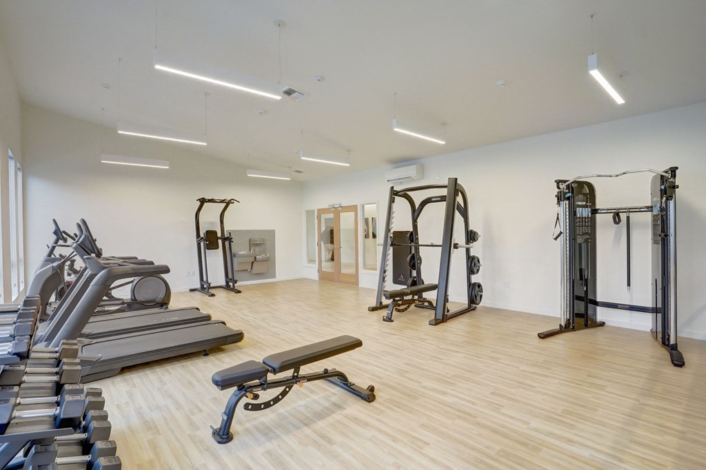 a gym with treadmills and weights in a building with white walls