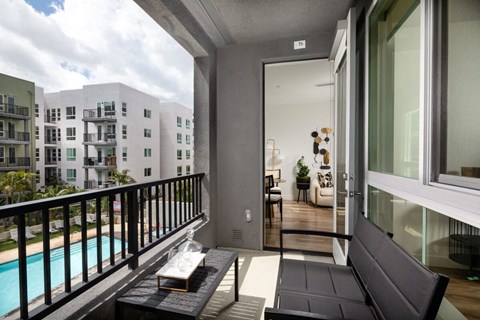 A balcony with a black couch and a pool in the background.