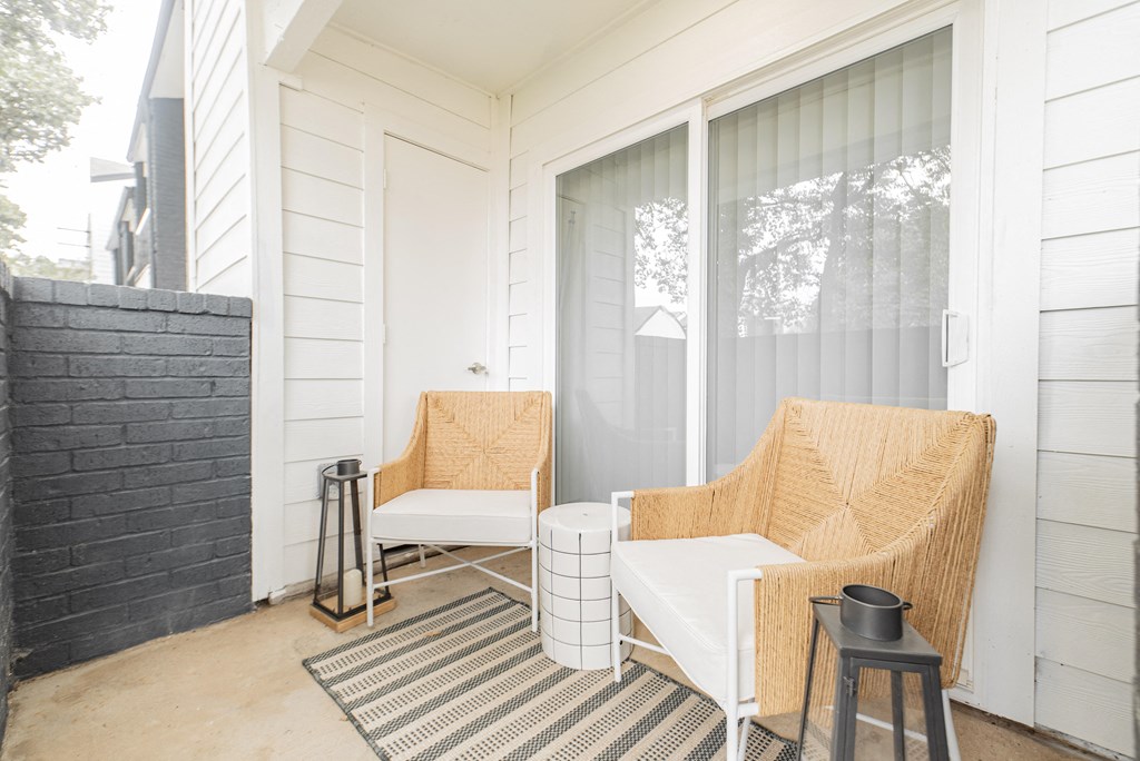a small porch with two chairs and a table and a door