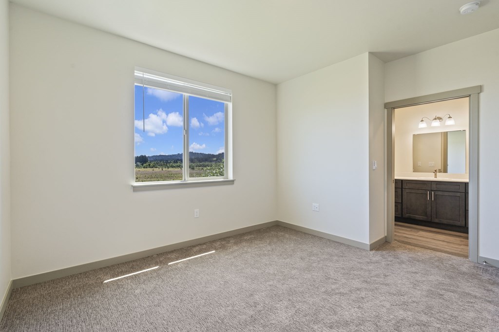 A room with a large window and a carpeted floor.