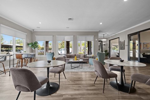 A modern dining room with a glass table surrounded by grey chairs.
