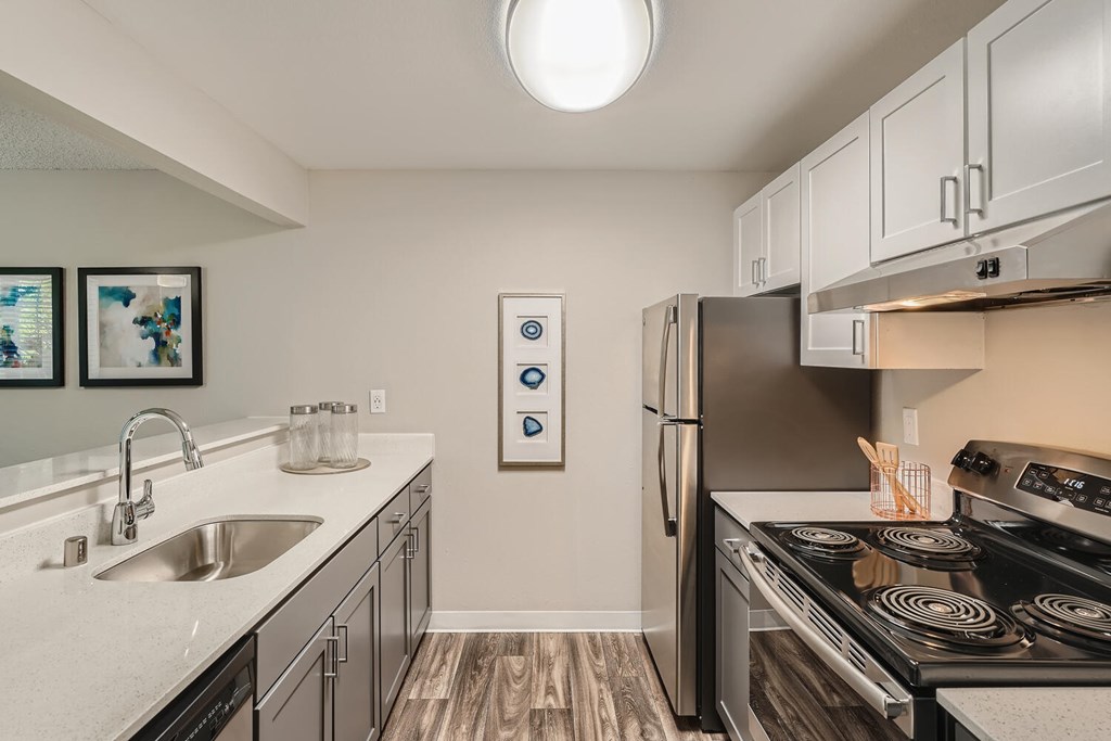 A modern kitchen with a stove, refrigerator, and sink.