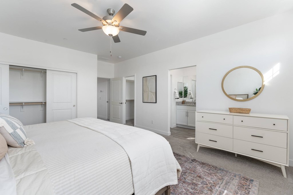 A bedroom with a large bed, a dresser, and a mirror.