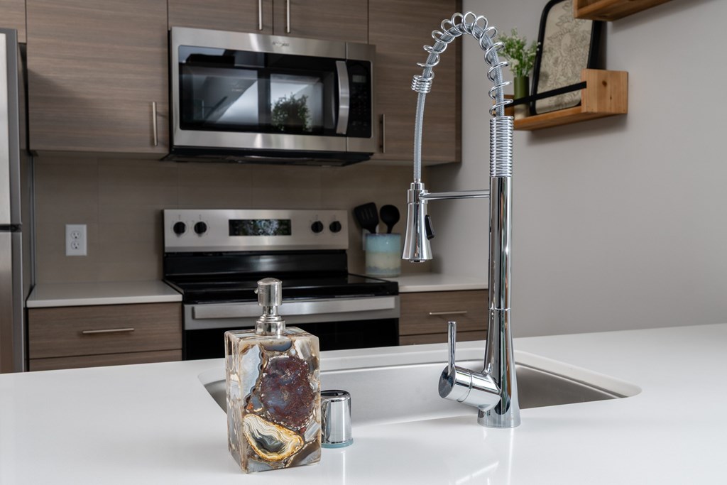 A kitchen with a white countertop and a silver faucet.