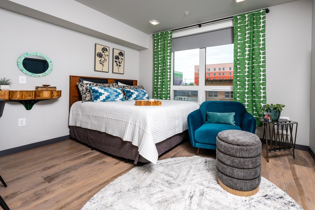 A bedroom with a bed, chair, and a rug.