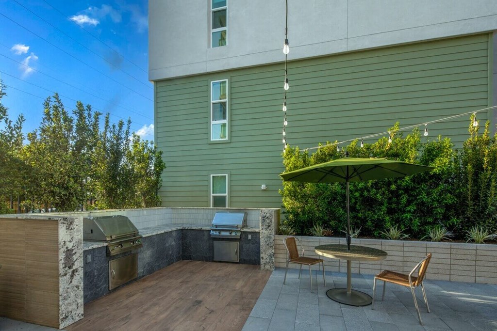 a patio with a grill and a table with chairs