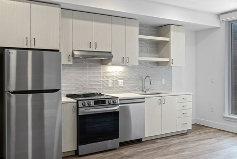 A modern kitchen with a stainless steel refrigerator and oven.