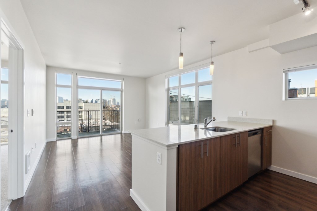 A kitchen with a white counter top and wooden floors.