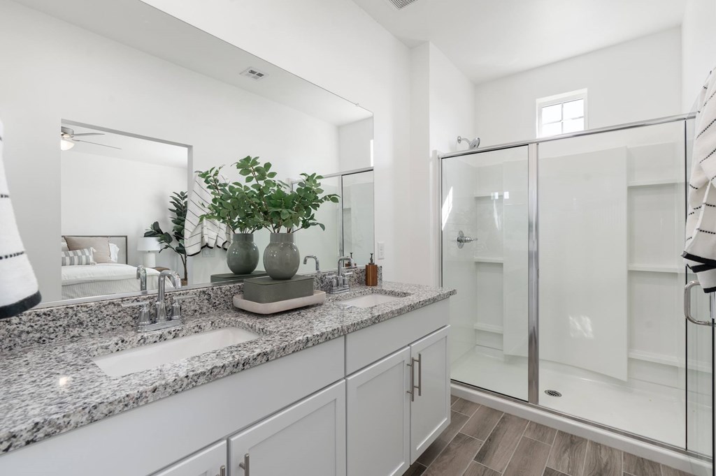 A bathroom with a marble countertop and a glass shower stall.