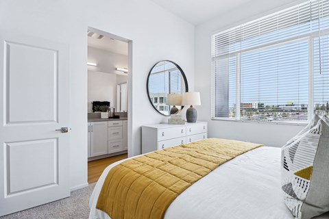 A bedroom with a large bed and a round mirror on the wall.