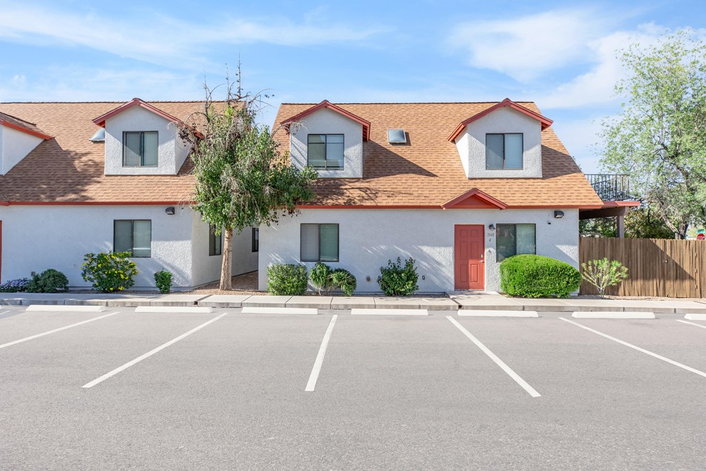 A white building with a red roof and a parking lot in front.