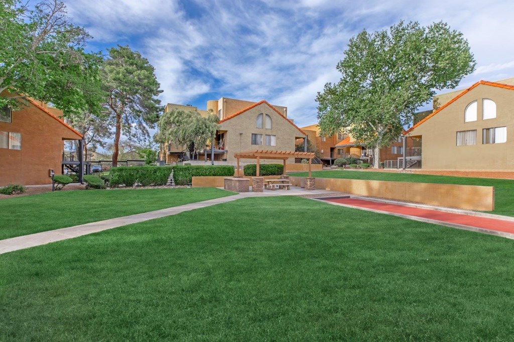 A grassy area in front of a building with a red track.