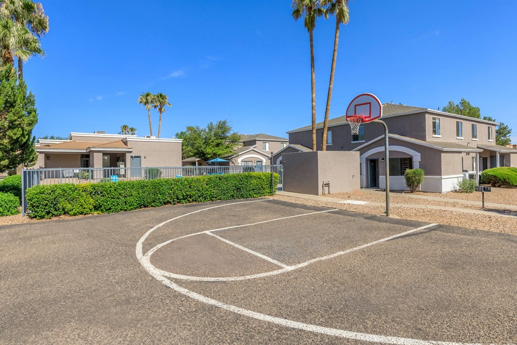 A basketball court is located in front of a building with a basketball hoop.