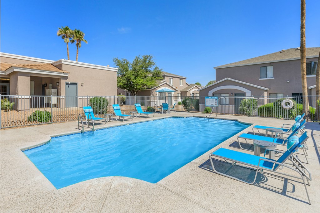 A swimming pool surrounded by lounge chairs and palm trees.