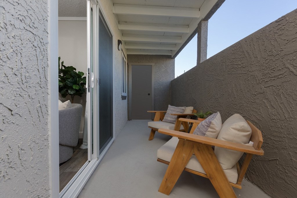 a seating area on a balcony with a table and pillows