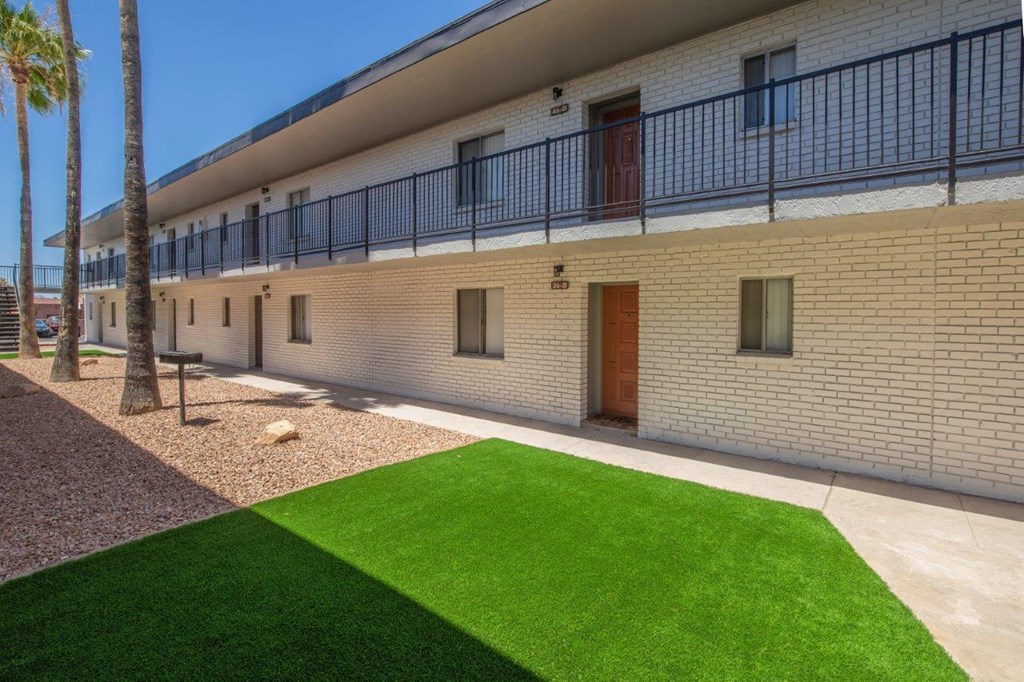 A building with a balcony and a green lawn in front.