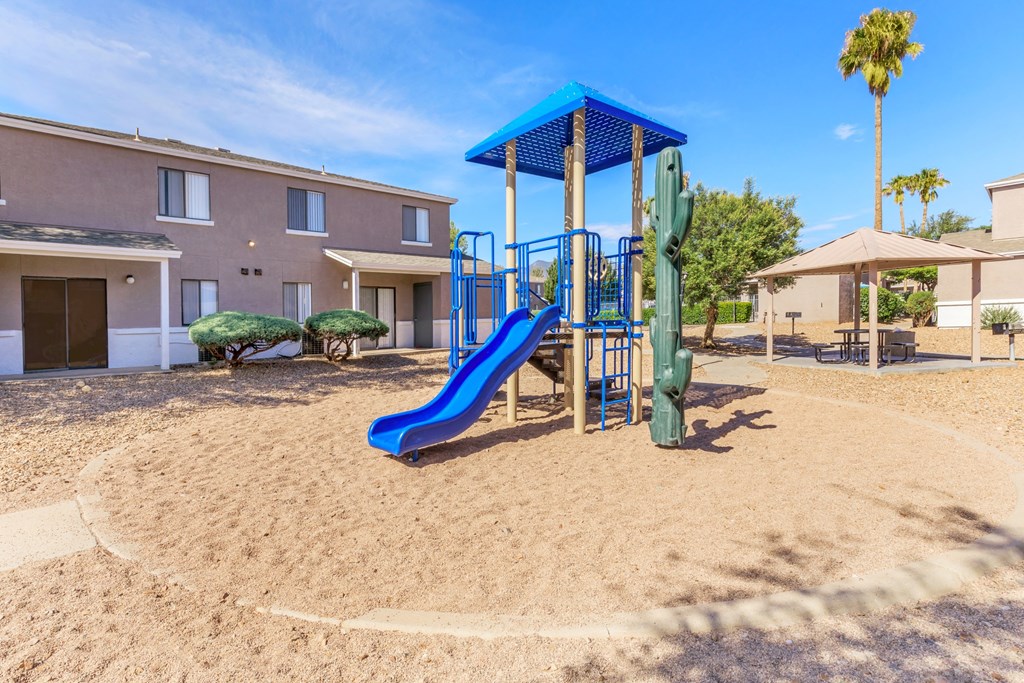 A playground with a blue slide and a green slide.