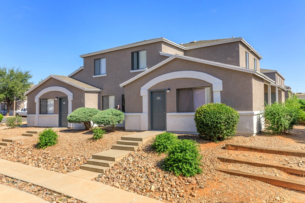 A modern house with a grey exterior and a landscaped front yard.