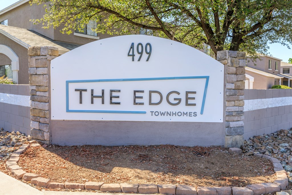 A sign for "The Edge" townhomes stands in front of a building.