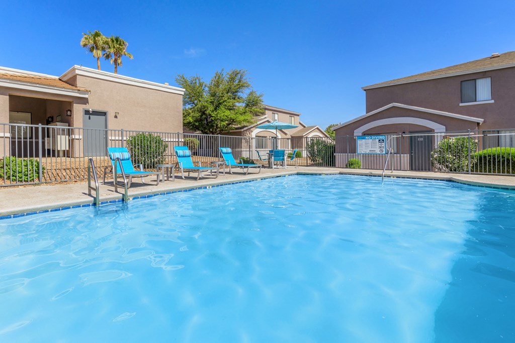 A swimming pool surrounded by chairs and a fence.