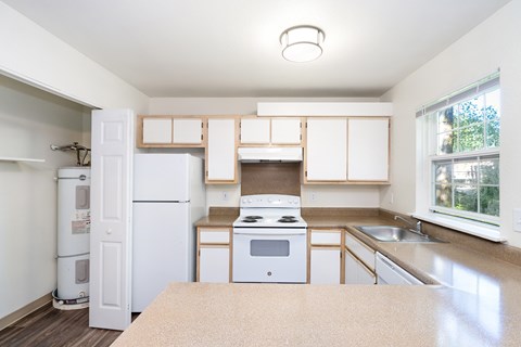 A kitchen with white appliances and wooden cabinets.