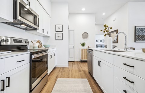 A modern kitchen with white cabinets and a wooden floor.