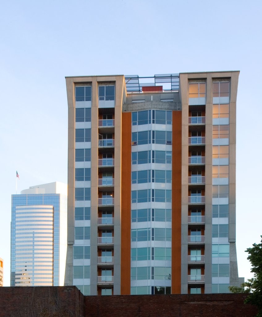 A tall building with a brown and blue facade stands in front of a smaller building.