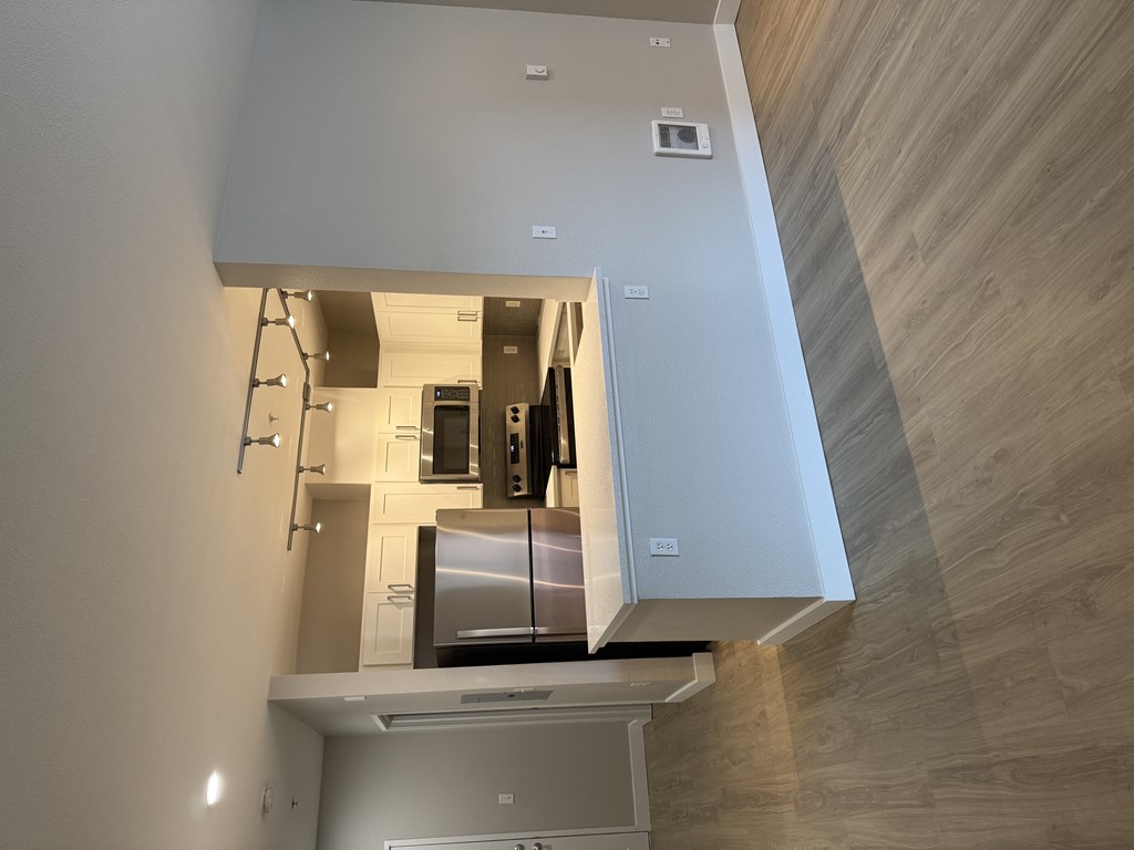 A modern kitchen with a stainless steel refrigerator and wooden accents on the walls.