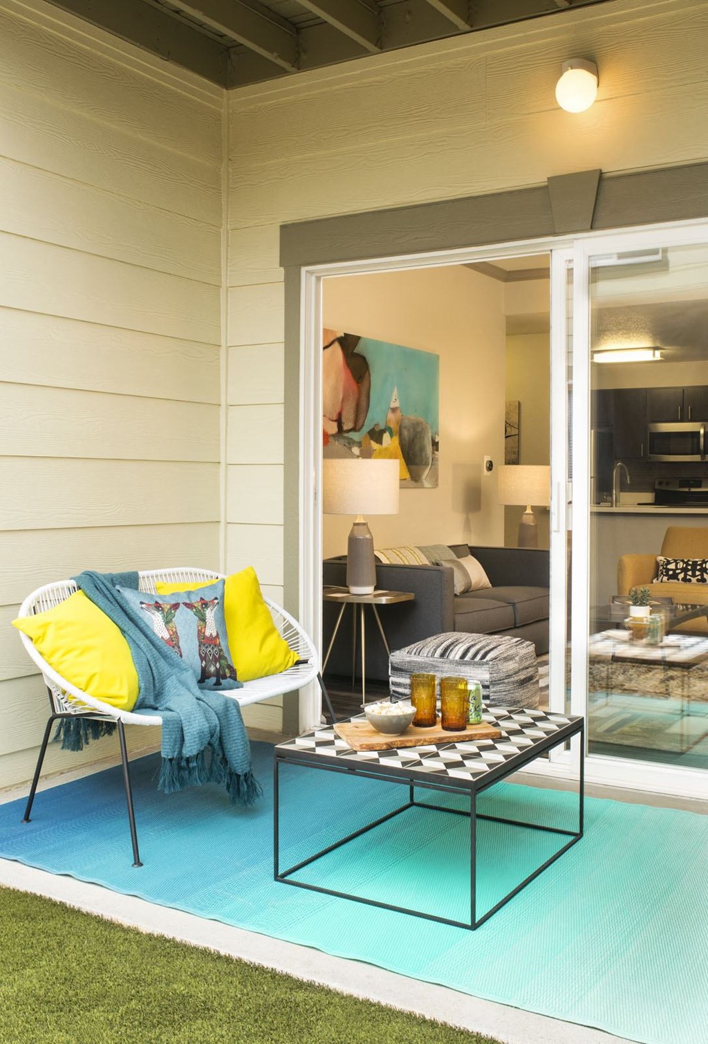 a patio with a white chair and a coffee table on a blue rug