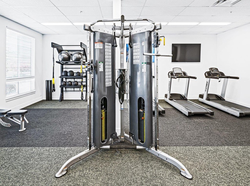 a gym with cardio equipment and a tv in a room
