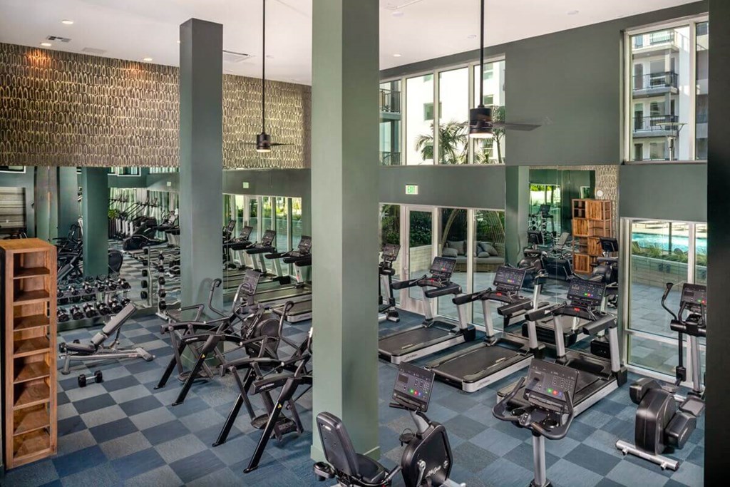 a large fitness center with cardio equipment and glass windows
