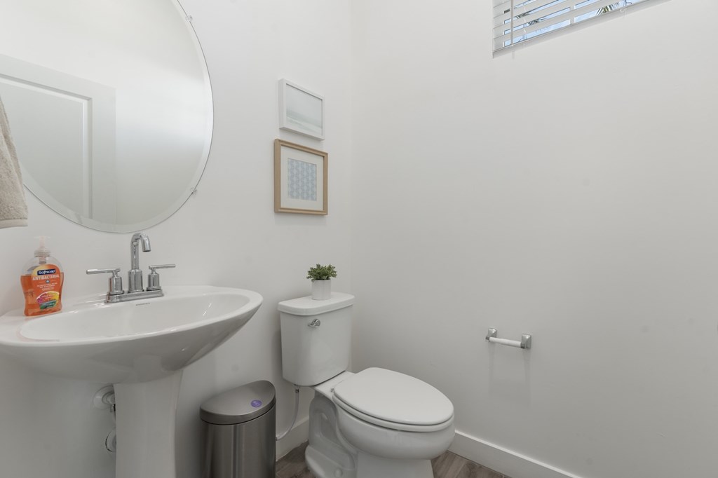 A white bathroom with a toilet, sink, and mirror.