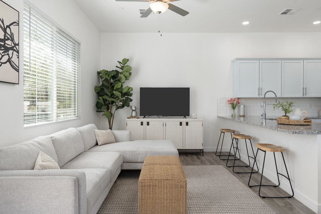 A living room with a grey couch, a television, and a bar area.