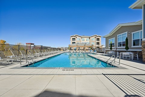 A swimming pool surrounded by lounge chairs and apartment buildings.