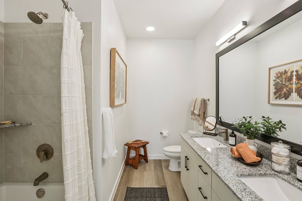 A bathroom with a white shower curtain and a white towel hanging on the shower rod.