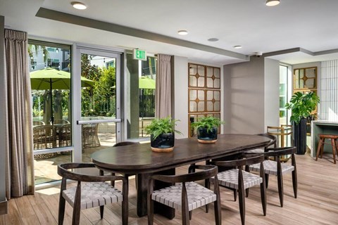 A dining room with a table and chairs and a window with a view of the outside.